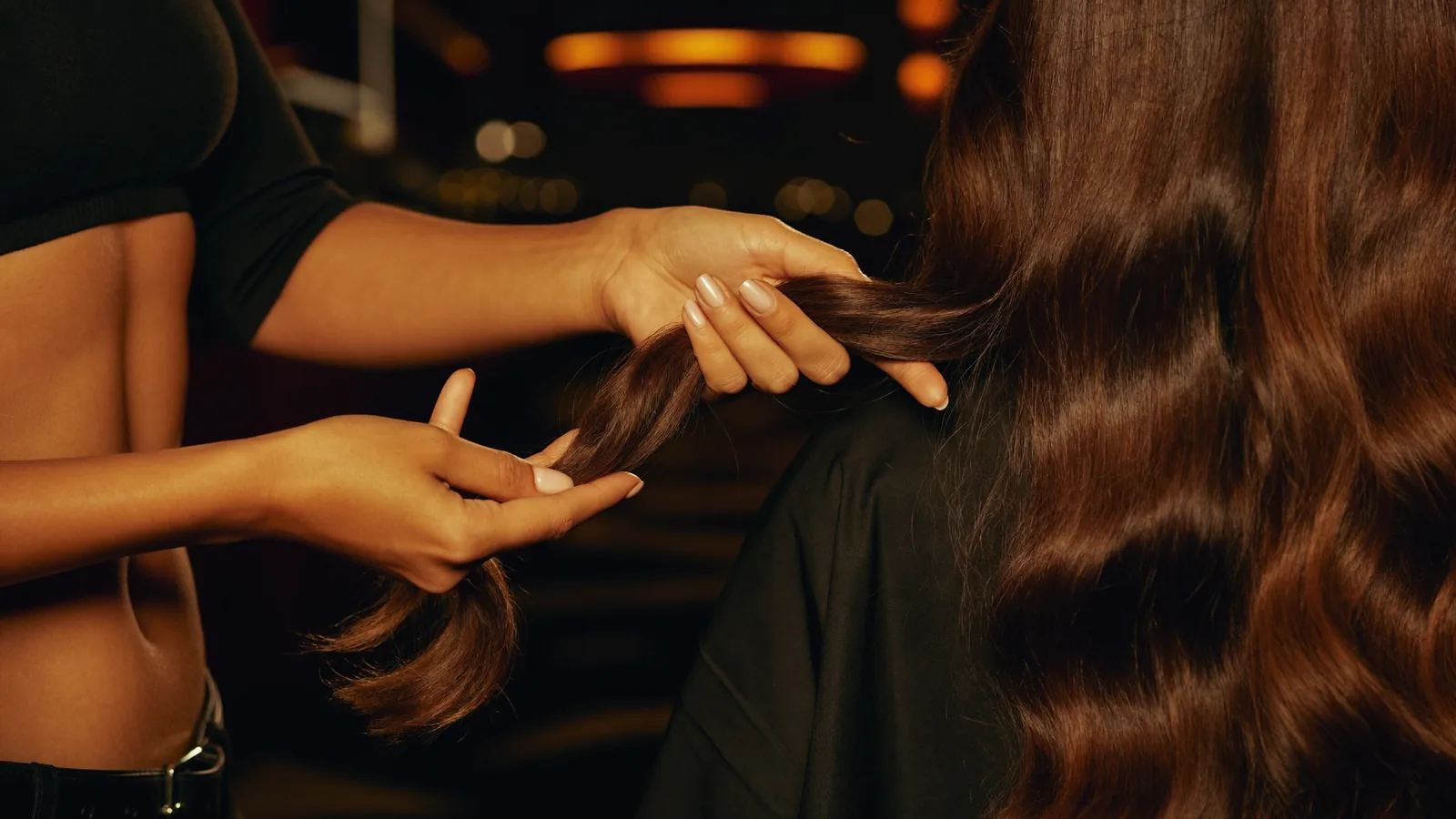 Friseurin prüft im Salon in Köln die Spitzen langer brünetter Haare auf Haarbruch und Spliss